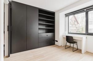 um armário preto num quarto branco com uma cadeira em Résidence Palace Expo em Bruxelas