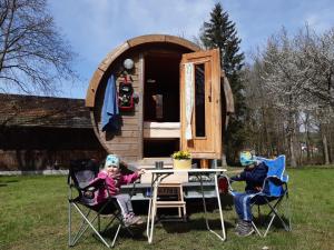 two children sitting at a table in front of a tiny house at Campingfass Almtal in Scharnstein
