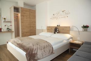 フェルトバッハにあるHotel & Frühstückspension Raabtalの白いベッド1台(木製ヘッドボード付)が備わるベッドルーム1室が備わります。