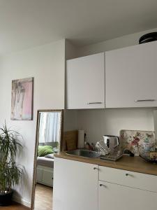 kuchnia z białymi szafkami, umywalką i lustrem w obiekcie Private room in Misburg, Hanover w Hanowerze