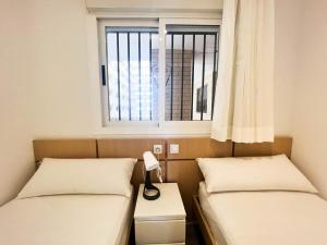 two beds in a room with a window at Dorado Amanecer frente al Mar in Oropesa del Mar
