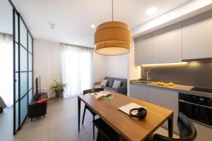 cocina y sala de estar con mesa de madera y comedor en Alidreams Lola Center Apartamentos, en Alicante