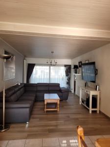 uma sala de estar com um sofá e uma televisão em Gezellige vakantiewoning Alice em Middelkerke