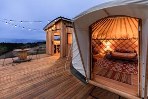 Luxury yurt glamping at Littlegrove في Adventure Bay: سرير كوخ القباني في شرفة على السطح