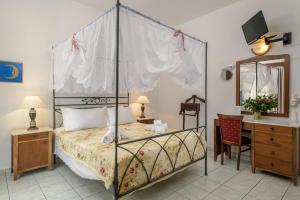 Grikos Hotel في Grikos: غرفة نوم مع سرير المظلة ومكتب