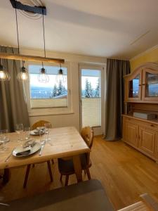 a dining room with a wooden table and two windows at Ferienwohnung Königsleiten 121a - Top 1 in Königsleiten