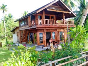 a wooden house with a balcony and a table at Mentawai Balcony in Masokut