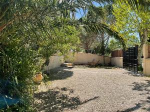 une cour avec une clôture, des arbres et un banc dans l'établissement Jolie maison entre mer et Narbonne, à Narbonne