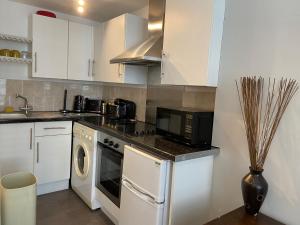 a kitchen with white cabinets and a stove top oven at Bristol Old City Studio in Bristol