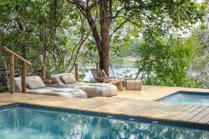 une piscine avec une terrasse en bois à côté d'une piscine dans l'établissement Tsowa Safari Island, à Victoria Falls