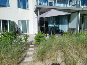 a patio with an umbrella in front of a house at FeWo Am Meer Prora in Binz