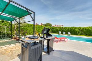 a outdoor kitchen with a grill and a swimming pool at Holiday Home Dori in Fažana