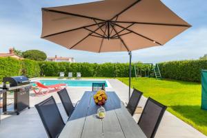 a table with an umbrella next to a pool at Holiday Home Dori in Fažana