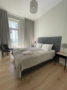 a white bedroom with a large bed and a window at Apartamenty Vincent Sopot in Sopot