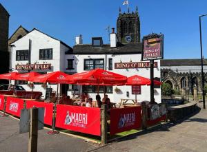 um restaurante com guarda-sóis vermelhos em frente a um edifício em The Ring O'Bells em Halifax