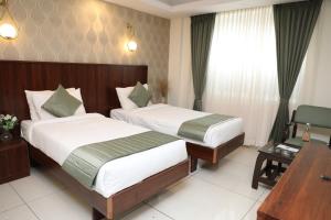 a hotel room with two beds and a desk at Earth Hotels in Bengaluru
