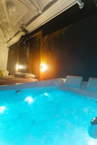 Una gran bañera azul en una habitación con cama en Capsule Art Déco - Jacuzzi - Netflix - Home Cinéma - Arcade de jeux & Nintendo switch - 2 chambres - Filet suspendu, en Valenciennes