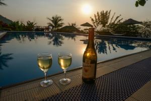 una botella de vino y dos copas junto a la piscina en Parkview Safari Lodge-Kyambura, en Busonga