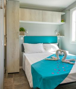 una camera da letto con un letto con due cigni sopra di Camping Atlanta & Mediterraneo Family Village a Sottomarina