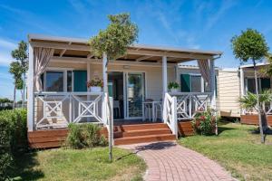 una casa con porche y terraza en Camping Atlanta & Mediterraneo Family Village, en Sottomarina