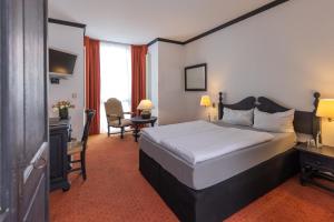 um quarto de hotel com uma cama, uma secretária e uma cadeira em Hotel Stadt Gütersloh em Gütersloh