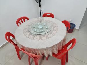 una mesa blanca con sillas rojas y un plato en ella en Sweethome Homestay Sandakan, en Sandakan