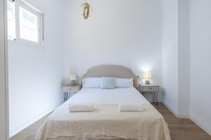 a white bedroom with a large bed with two tables at Urbe10 Terrace Constitucion 1 Bedroom Apartment in Málaga