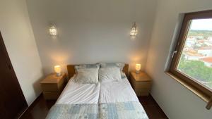 una camera da letto con un letto con due comodini e una finestra di Casa do Miradouro a Carrapateira