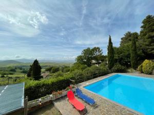 a pool with two chairs and a view of the countryside at Casa Bianca Villa pool with sea view, fenced garden, barbecue by ToscanaTour in Castellina Marittima