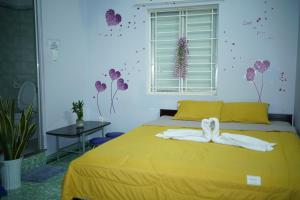 Jaymo Motel في فنغ تاو: غرفة نوم بسرير اصفر وفوط بيضاء