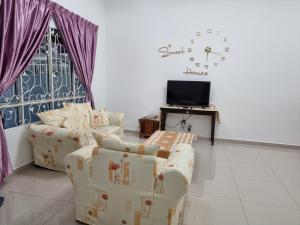 a living room with a couch and a tv at Sweethome Homestay Sandakan in Sandakan