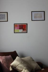 two framed pictures on a white wall with a couch at Buzzing Retreat in Velika Remeta