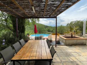 einen Holztisch und Stühle auf einer Terrasse mit einem Pool in der Unterkunft Villa Champie in Pradons