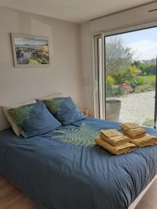 una camera da letto con un letto con lenzuola blu e una finestra di Chambre d'hôte Milin An Awel a Pleumeur-Bodou