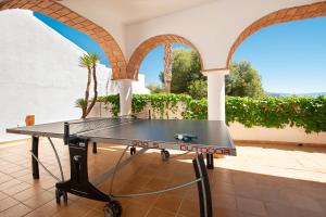 a ping pong table in a courtyard with arches at Lovely villa with jacuzzi and heated pool in Almuñécar