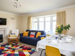 a living room with a table and a blue couch at Homely 4-Bed House close to stunning beach in Pwllheli