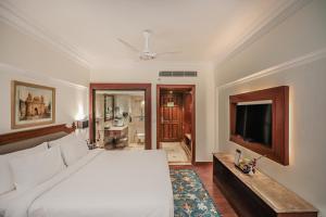 Schlafzimmer mit einem weißen Bett und einem TV in der Unterkunft Regenta Central Lucknow by Royal Orchid Hotels Limited in Lucknow