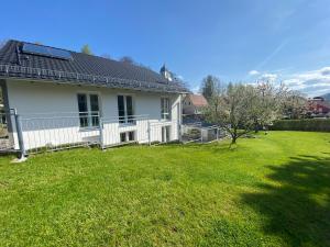 a white house with a fence and a yard at Ferienhaus „Am Sandstein“ in Papstdorf