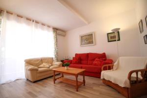 a living room with a red couch and a table at Mediterranean Way - Punta Prima in La Pineda