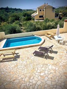 a swimming pool with two lounge chairs and a table at villamaria in Makrádes