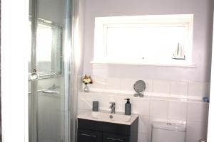 a bathroom with a sink and a toilet and a window at Gorgeous 3 bed House In Milton Keynes in Bletchley