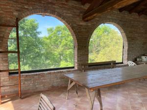 comedor con 2 ventanas arqueadas y mesa de madera en Casa in sasso con piscina, en Vernasca