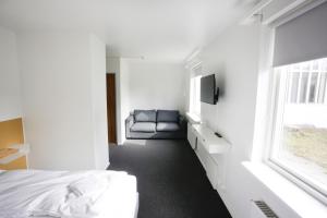 1 dormitorio con 1 cama, 1 silla y 1 ventana en Eiðar - Hostel en Eiðar