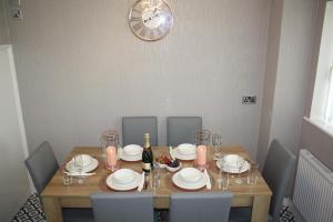 a dining room table with chairs and a clock on the wall at Gorgeous 3 bed House In Bletchley Milton Keynes in Bletchley