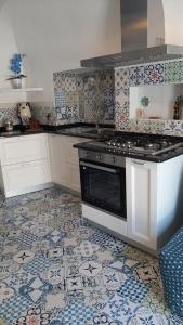 a kitchen with a stove and a tile floor at Petit Maison Jeranto in Nerano