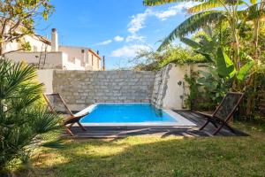 a swimming pool in a yard with two chairs at Loft Favoloso con piscina in Tortolì