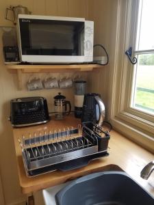 a kitchen counter with a microwave and a sink at Rhydydefaid Cwt Clyd - Cosy Hut in Bala
