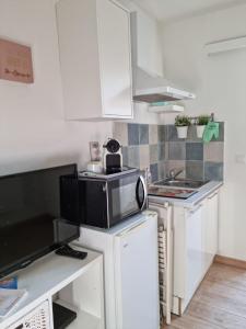 kuchnia z białymi szafkami i mikrofalówką w obiekcie Le Secret de Sanary w mieście Sanary-sur-Mer