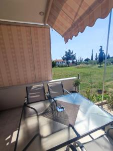 uma mesa de vidro e cadeiras com vista para um campo em A & F Apartments - Fay's house em Kalivia Poligirou