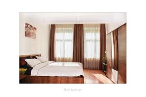 1 dormitorio con 1 cama con sábanas blancas y ventanas en Apartament Dinicu, Brasov, Romania, en Brasov